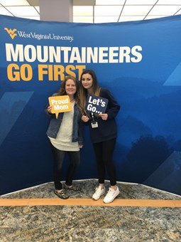 Amara Garity and her mother Jamie stand in front of a background that reads "Mountaineers go first"