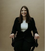 Professionally dressed Kennedy Scarry seated in office chair.