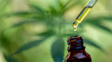 Picture of brown bottle with oil dropper above it with hemp in the background